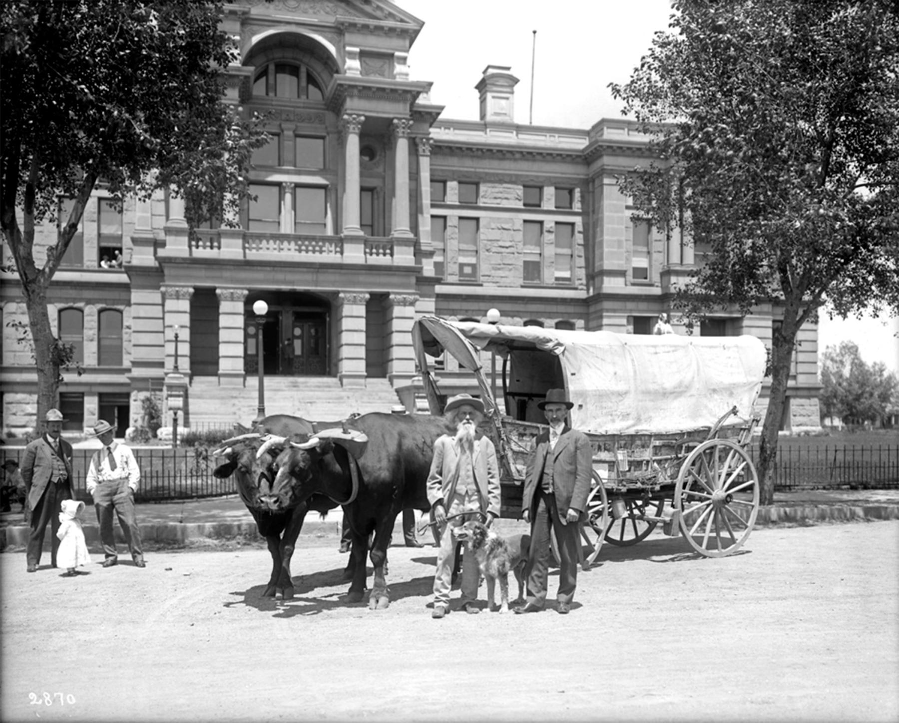Late in life, Ezra Meeker crossed the continent four times—twice with wagon and ox team, once by automobile and once in a biplane. Here, with two other men and a small girl looking on, he meets with Wyoming Gov. B.B. Brooks outside the State Capitol, 1910. Simson photo, Wyoming State Archives.