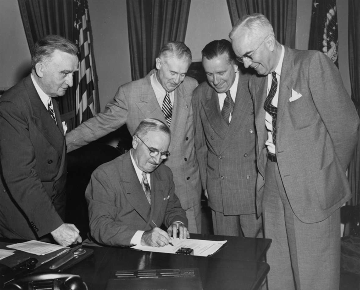 President Harry Truman signs a bill as Wyoming’s two U.S. senators, Joseph O’Mahoney, left, and Hunt, second from left, look on. The other two men are unidentified. Wyoming State Archives. President Harry Truman signs a bill as Wyoming’s two U.S. senators, Joseph O’Mahoney, left, and Hunt, second from left, look on. The other two men are unidentified. Wyoming State Archives.