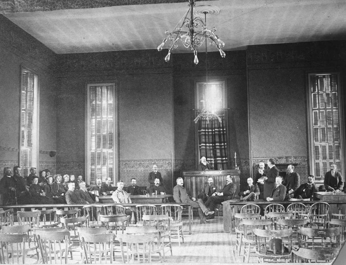 Judge Jacob B. Blair re-enacted the scene of the first woman jurors in his courtroom in Laramie in the mid 1880s. Women are seated at left in the front row of the jury box. Lawyer Melville C. Brown, the tall man at right looking at the judge, initially opposed jury service by women but later changed his mind. American Heritage Center.