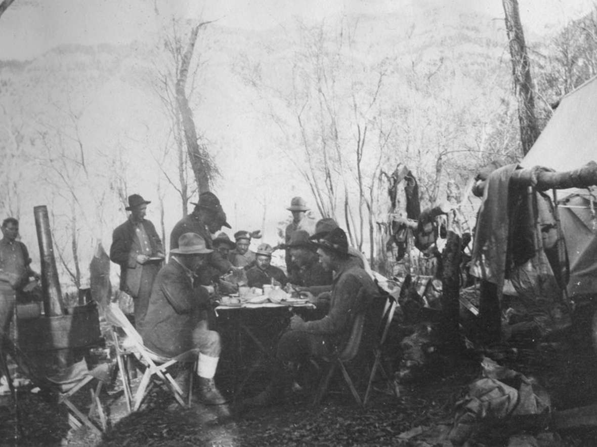 Charles “Spend-a-Million” Gates, at the head of the table, and his hunting party eat a meal prepared by the camp cook on their guided hunt into the Thorofare wilderness, October 1913.. Park County Archives. Charles “Spend-a-Million” Gates, at the head of the table, and his hunting party eat a meal prepared by the camp cook on their guided hunt into the Thorofare wilderness, October 1913.. Park County Archives.
